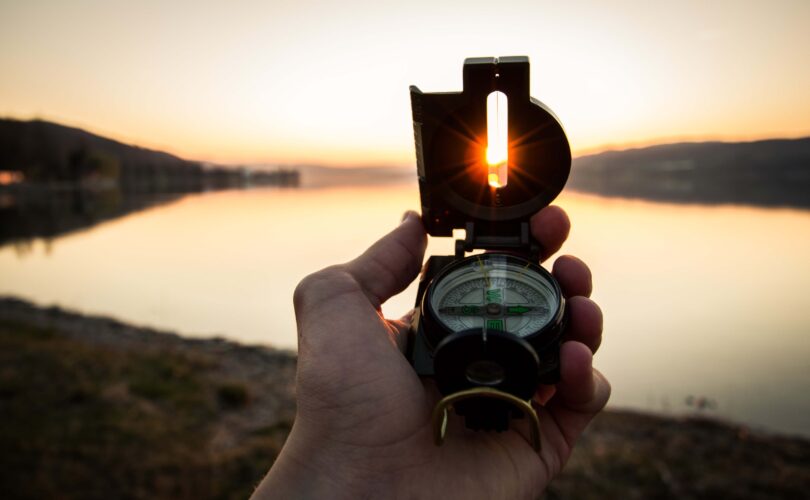 holding a compass pointed west Infront of an open lake