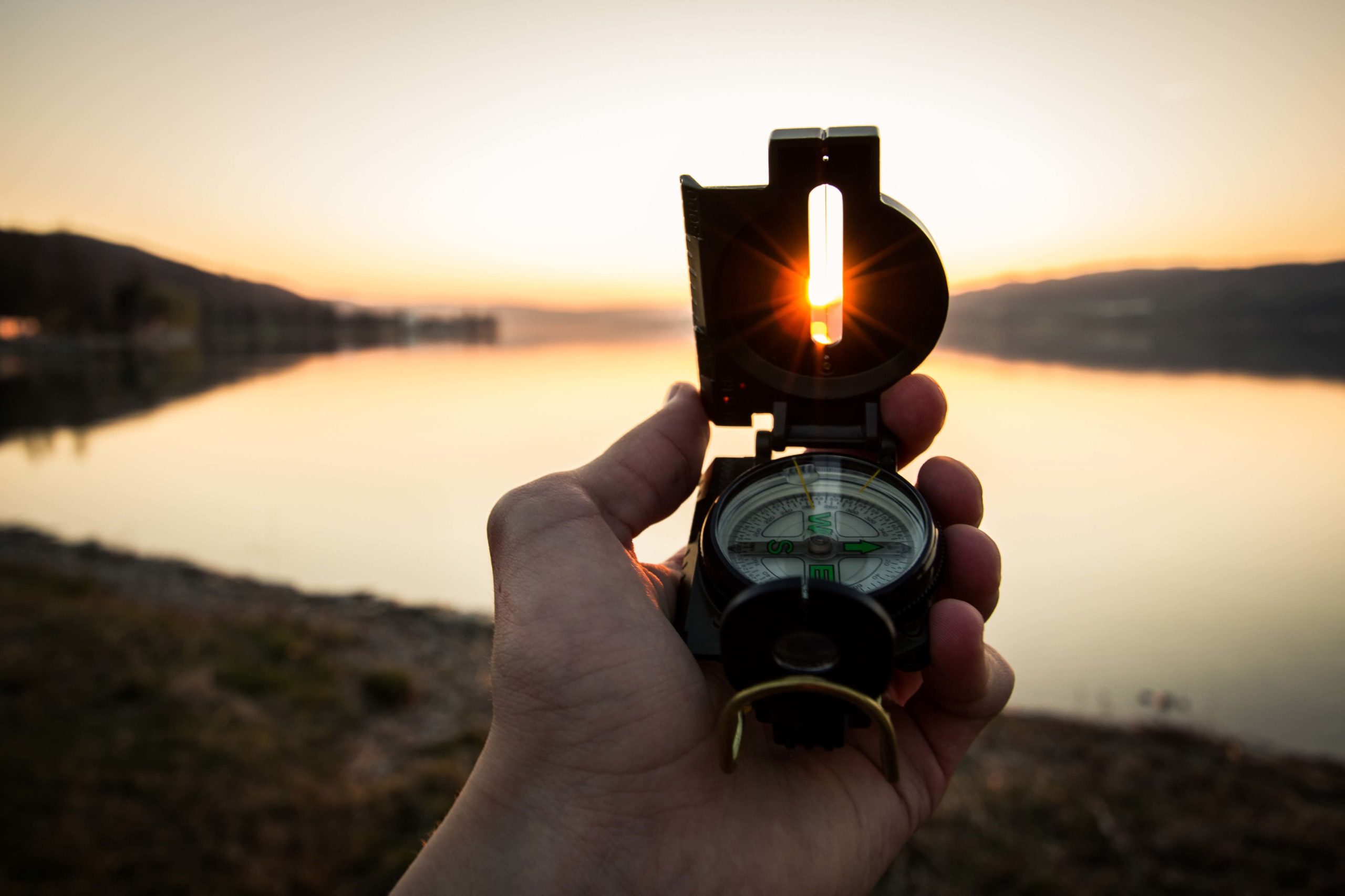 holding a compass pointed west Infront of an open lake